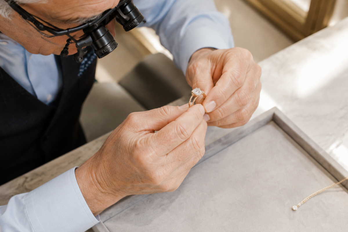 Illustrative overhead view of an experienced jewelry specialist inspecting a ring through professional magnifying spectacles.