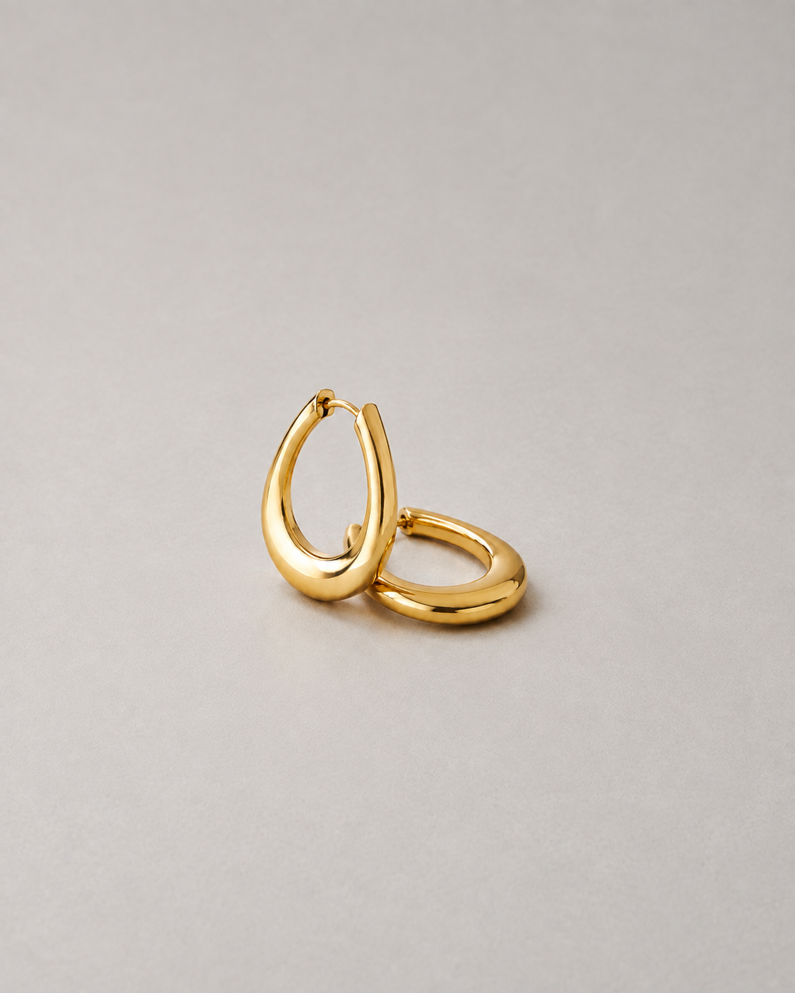 Editorial illustration of gold-tone hoop earrings with generous negative space and balanced contemporary contours.