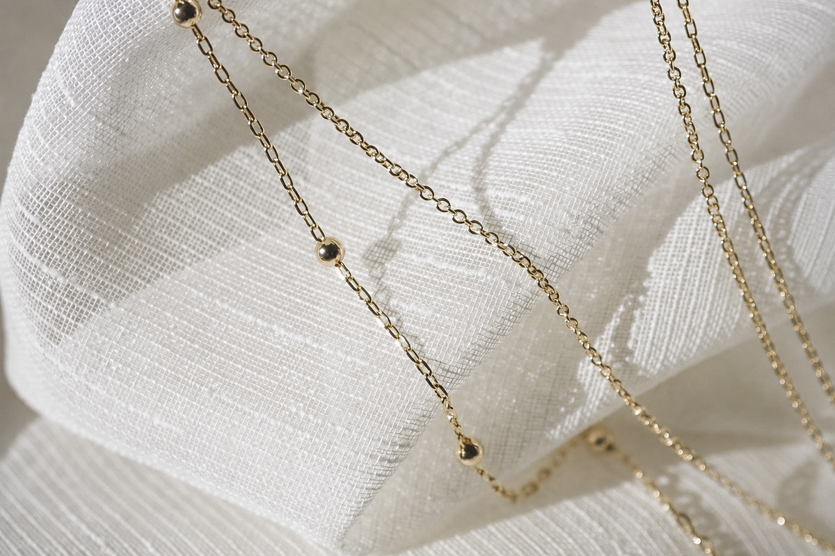 Fine gold-colored chains on white fabric, an illustrative study of metal finish.